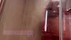 A thick baddie in a glass shower washes her big ass and tempts