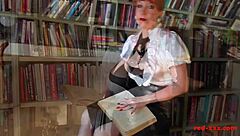 A sexy MILF with red hair pleases herself with a finger in her private library
