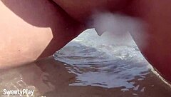 A mature woman with a curvaceous body urinates outdoors at the beach