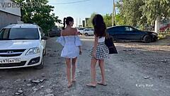 Two girls tease in public, flashing pussies without panties, small tits bouncing outdoors.