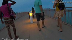 brunette flashes tits and ass while giving double handjob to big black monster cocks on public beach