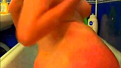 tattooed model in bathroom playing with glass dildo and fingering herself