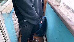 Slender brunette gives a public blowjob on a balcony