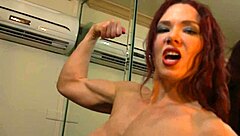 Fit redhead shows off her muscular physique in front of a mirror