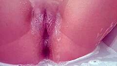 Is this milf masturbating her shaved pussy in the bath?