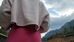 A woman masturbates outdoors near the mountains, reaching orgasm in the fresh air.